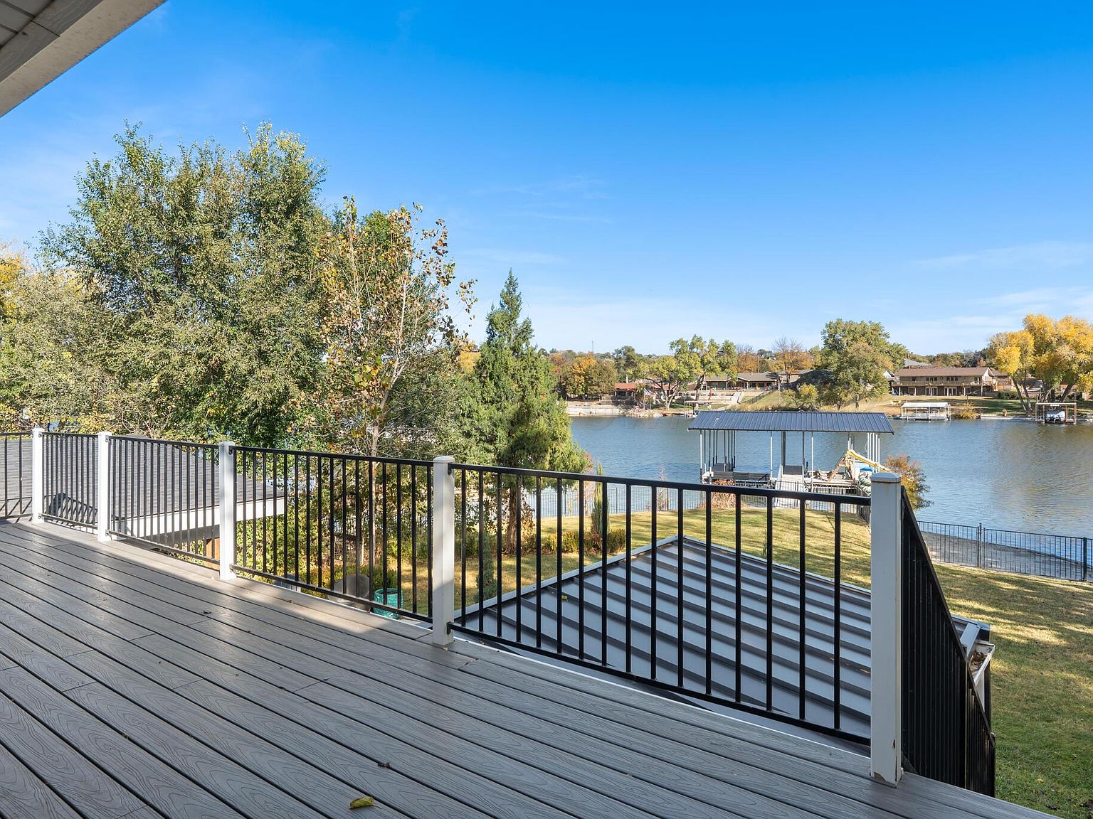 Covered balcony above the calm cove of Lake Tanglewood at 147 S Shore Dr, with open water, the new private dock with boat lift, and a tree-lined far shore.